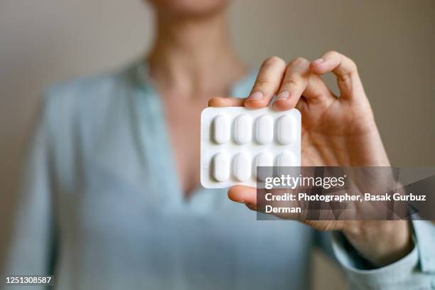 a woman's hand holding a blister pack of pills - blister pack stock-fotos und bilder