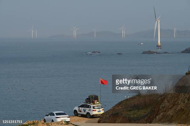Man sets up a Chinese flag on his car as he prepares to look at the view of the Taiwan Strait, towards the zone where China said it would conduct...