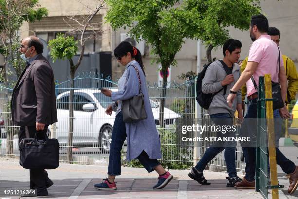 An unvailed Iranian woman walks in a street in Tehran on April 10, 2023. - Police in Iran said on April 8 they plan to use "smart" technology in...