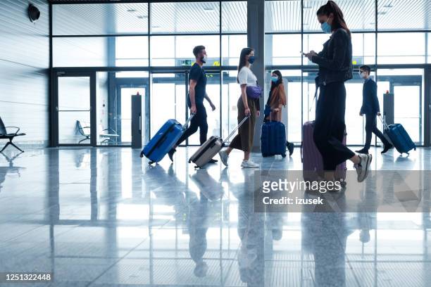 passengers at the airport with luggage, wearing n95 face masks - airport stock pictures, royalty-free photos & images