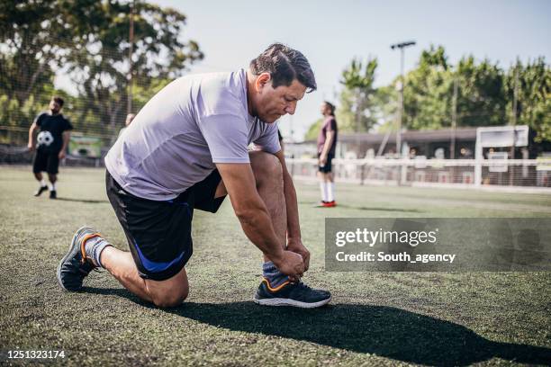 men tying shoelace outdoors on soccer field - tied up stock pictures, royalty-free photos & images