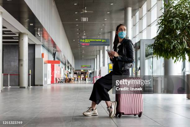 joven en el aeropuerto con equipaje, con máscaras faciales n95 - journey fotografías e imágenes de stock