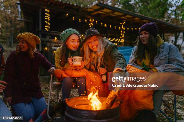 freundinnen genießen am lagerfeuer - lagerfeuer stock-fotos und bilder