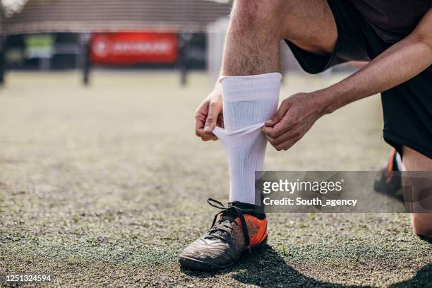 サッカー場で靴下を固定する男性サッカー選手 - socks ストックフォトと画像