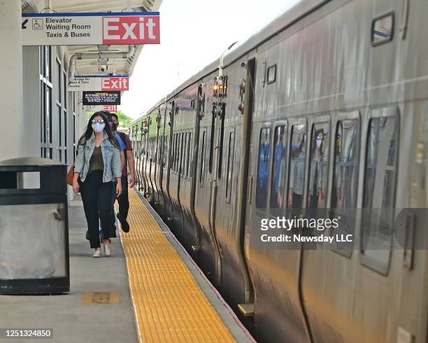 People wearing masks walk on the platform at the Hicksville LIRR train station on June 8, 2020.