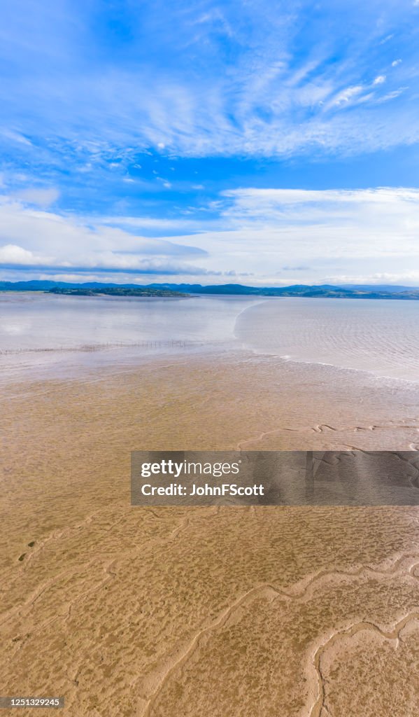 Vertikal panoramautsikt över sanden när tidvattnet kommer in på en solig morgon i sydvästra Skottland