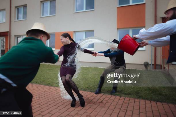 Boys and younger men from the Ilosvai Selymes Peter folk dance group pour buckets of cold water on a girl as they attend the traditional watering of...