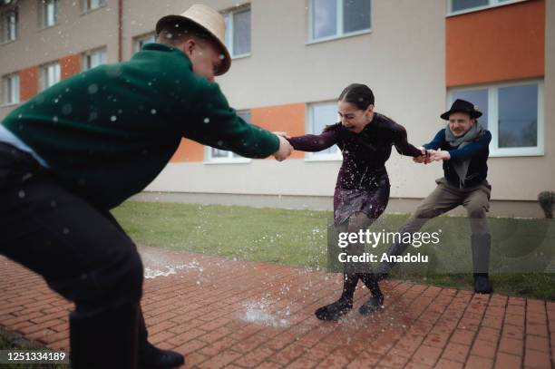 Boys and younger men from the Ilosvai Selymes Peter folk dance group pour buckets of cold water on a girl as they attend the traditional watering of...