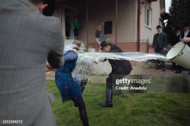 Boys and younger men from the Ilosvai Selymes Peter folk dance group pour buckets of cold water on a girl as they attend the traditional watering of...