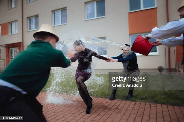 Boys and younger men from the Ilosvai Selymes Peter folk dance group pour buckets of cold water on a girl as they attend the traditional watering of...