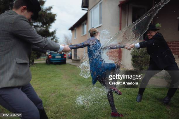 Boys and younger men from the Ilosvai Selymes Peter folk dance group pour buckets of cold water on a girl as they attend the traditional watering of...