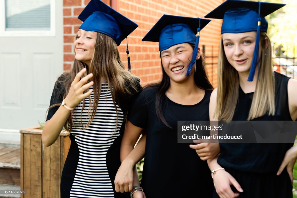 Teenage girls graduation from primary school portrait in backyard.