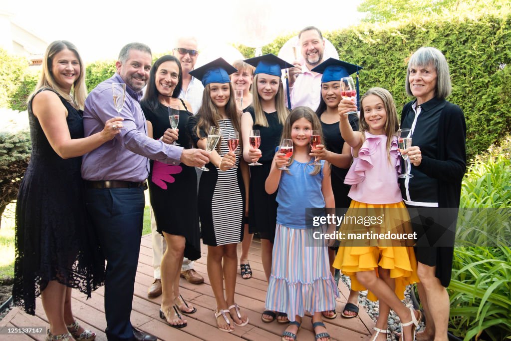 Teenage girls graduation from primary school family portrait in backyard.