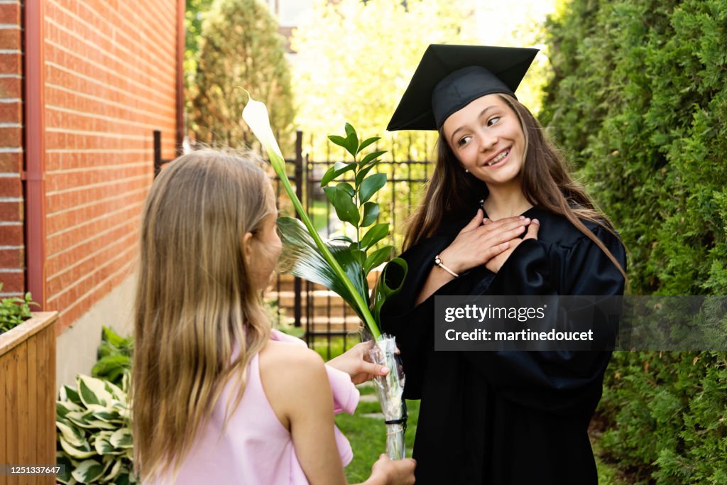 Teenage girl graduation from primary school portrait in backyard.