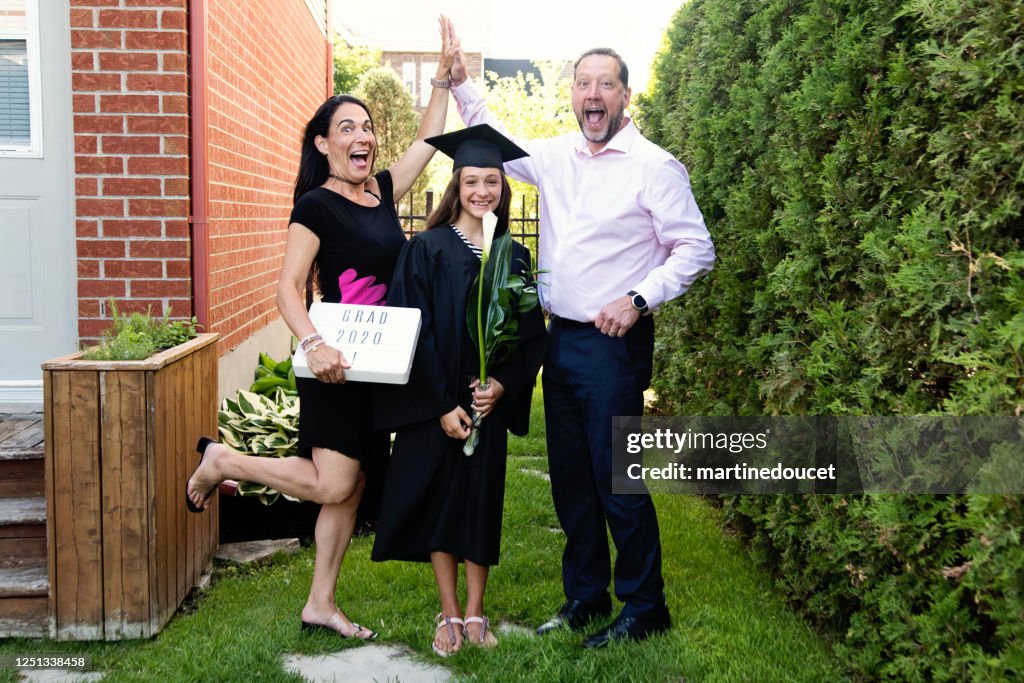 Adolescente graduada del retrato de la familia de la escuela primaria en el patio trasero.