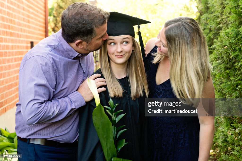 Teenage girl graduation from primary school family portrait in backyard.