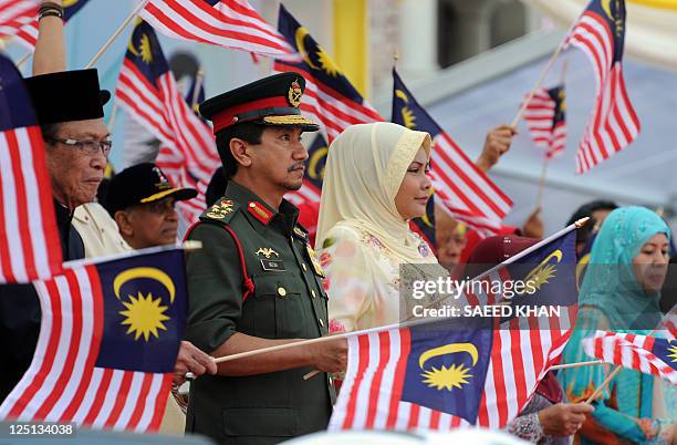Malaysia's King Sultan Mizan Zainal Abidin waves a national flag during the Malaysia Day and Independence Day parade in Kuala Lumpur on September 16,...
