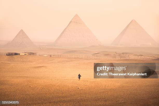 horse riding among hazy desert at giza pyramid complex in egypt - gizeh stockfoto's en -beelden