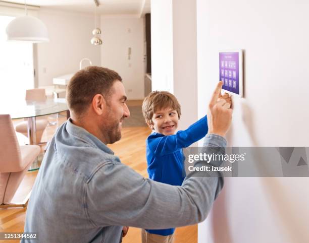 vater mit sohn steuert intelligente geräte mit einem digitalen tablet zu hause - home technology stock-fotos und bilder