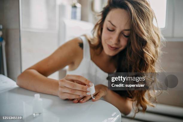young woman paints her nails - unha imagens e fotografias de stock