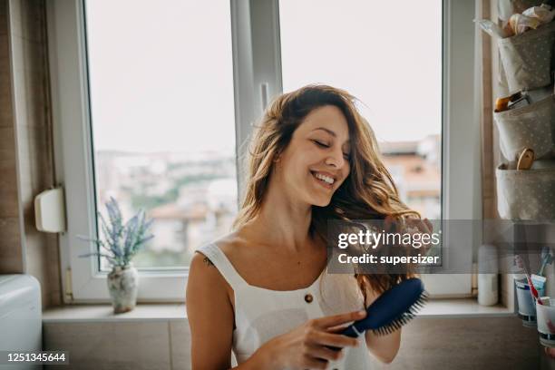 young woman combing hair - comb hair care stock pictures, royalty-free photos & images