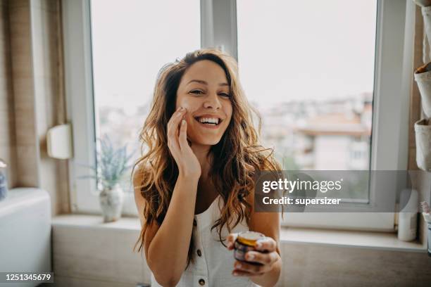 young woman applies facial cream - beauty product woman stock pictures, royalty-free photos & images