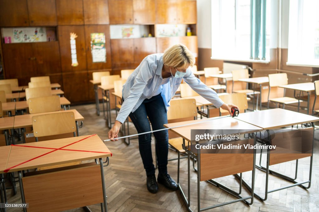 COVID-19. El maestro marca lugares vacíos en el salón de clases