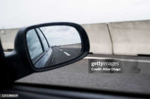 view of the road through the window of a car and its rearview mirror while driving on the road in a cloudy day. germany. - side view mirror stockfoto's en -beelden