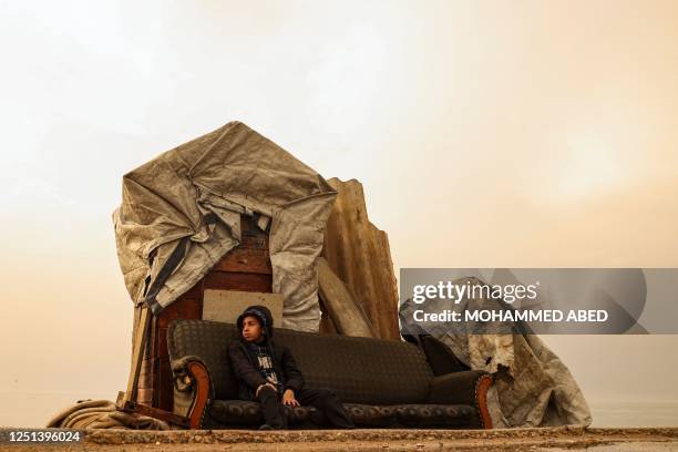 Palestinian boy sits on a couch by the beach near his home at sunset in Gaza city, on April 10, 2023.