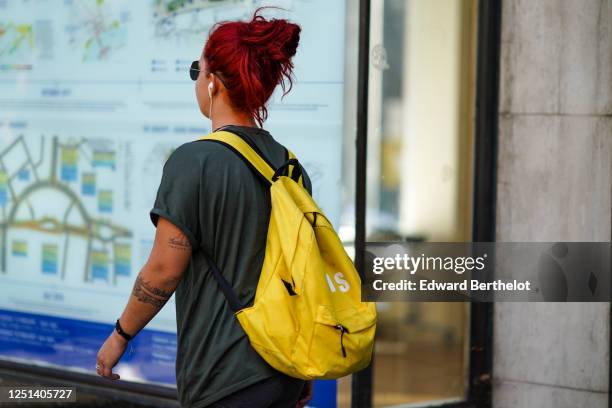 Guest wears a khaki t-shirt, a yellow backpack, during London Fashion Week September 2019 on September 13, 2019 in London, England.