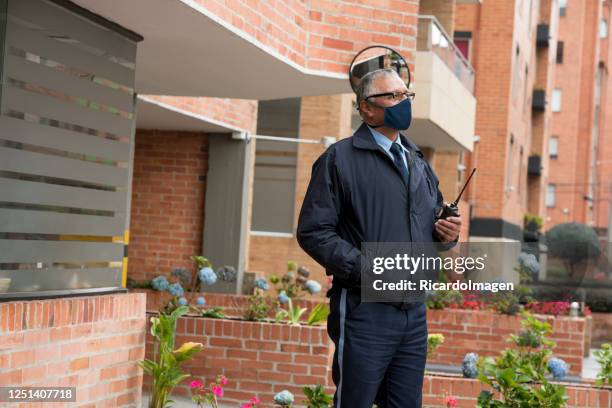 building doorman looks at the camera in a portrait while wearing his mask to avoid the covid 19 - bouncer guarding stock pictures, royalty-free photos & images