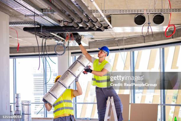 mann richtet lüftungsanlage in innenräumen ein - installationskunst stock-fotos und bilder