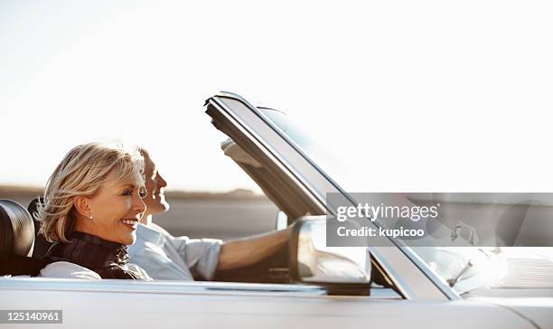 happy senior woman riding in a car with her husband - convertible stockfoto's en -beelden