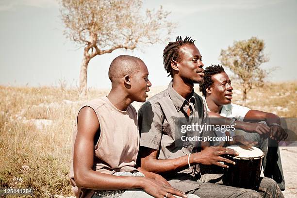 tre africani che giocano djembe nel prato - djembe foto e immagini stock