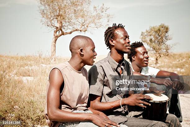 three africans men playing djembe in the meadow - yembe stock pictures, royalty-free photos & images