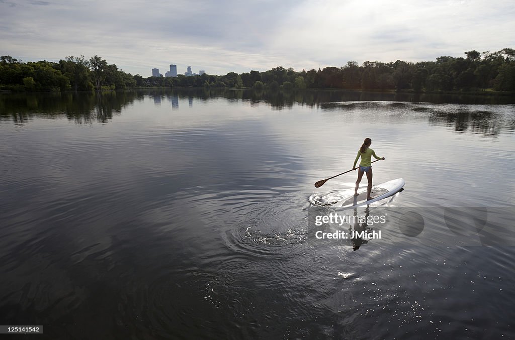 Athletic Woman Paddle Boarding on a Calm Midwestern Lake.