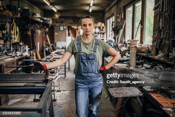 junge arbeiterin steht in der werkstatt - wood worker posing stock-fotos und bilder