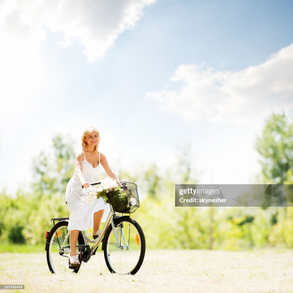 Beautiful blonde woman riding a bicycle.