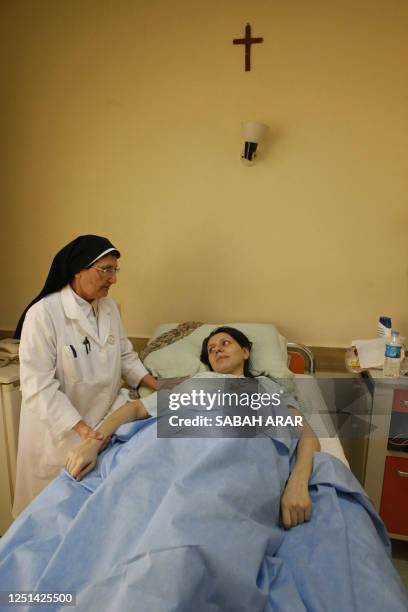 An Iraqi nun tends to a wounded Christian woman, who survived last week's church carnage in Baghdad, at a hospital in the Iraqi capital on November 7...