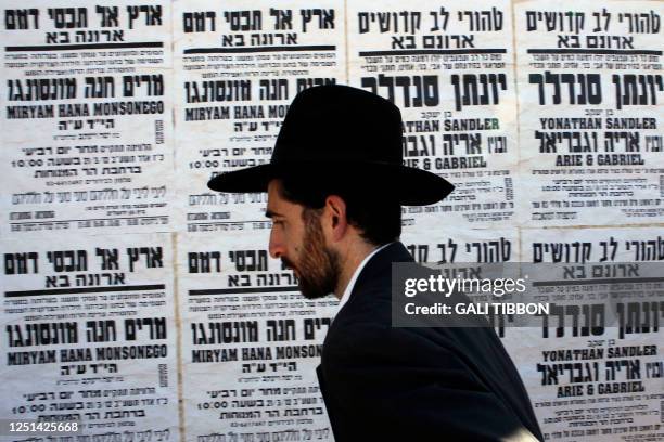 An Israeli Orthodox Jew walks past death notices mourning the killing of four Jews in southern France this week in Jerusalem on March 22, 2012....