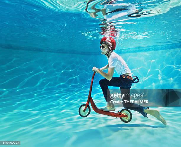 teenager pushing a scooter underwater - gek worden stockfoto's en -beelden