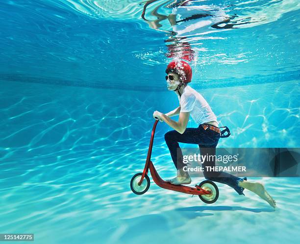 teenager pushing a scooter underwater - bizarre bildbanksfoton och bilder