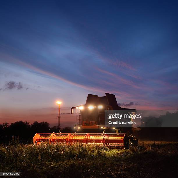 combine working on the field by night - combine stockfoto's en -beelden