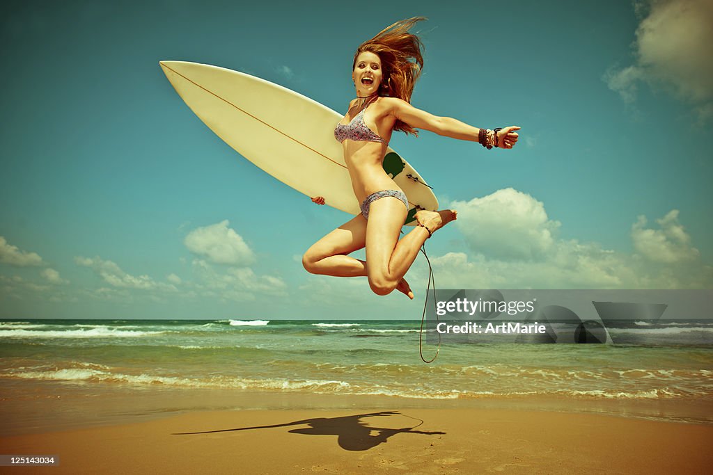 Junge Frau springen mit surf-board am Strand