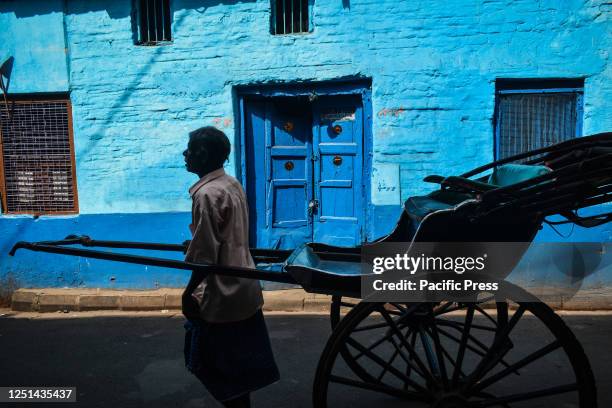 Man with hand-pulled rickshaw passes on the street on a hot summer day in Kolkata.