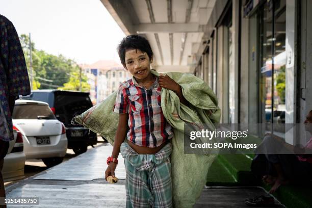 Boy, referred to as a "trash collector", is seen carrying a bag of recycling while walking on the street in Yangon. Since the coup, funding for...