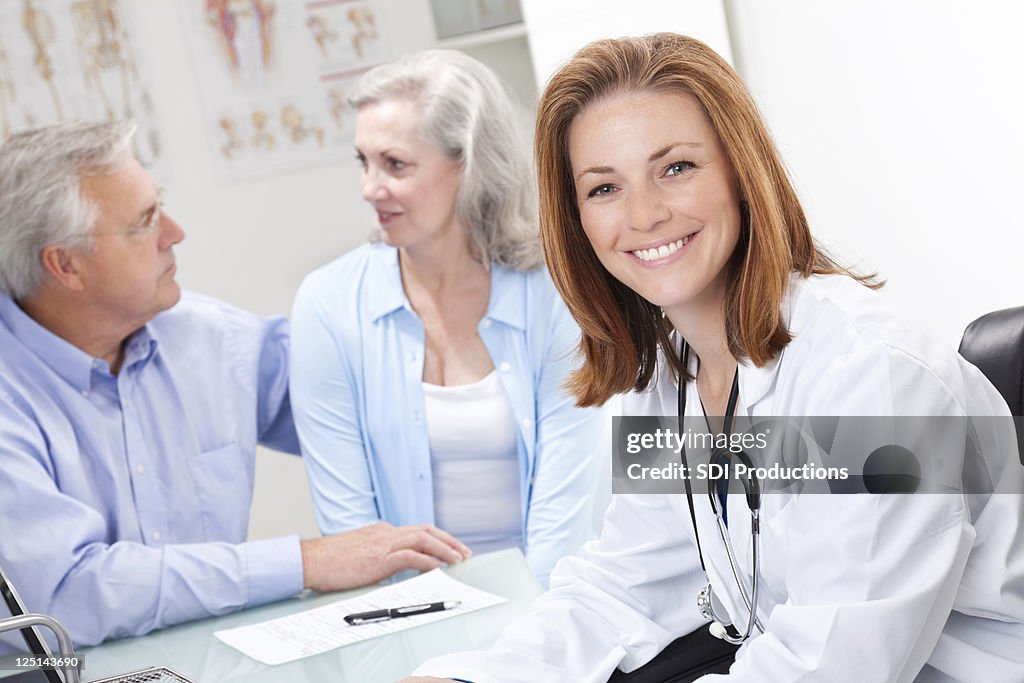 Medico alla scrivania sorridente riunione di Senior coppia adulta