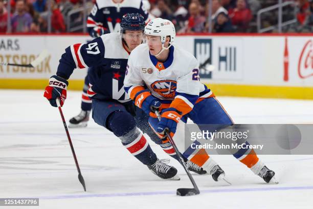 Sebastian Aho of the New York Islanders protects the puck from a pursuing Beck Malenstyn of the Washington Capitals during a game at Capital One...