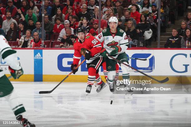 Tyler Johnson of the Chicago Blackhawks and Matt Boldy of the Minnesota Wild chase the puck in the first period at United Center on April 10, 2023 in...