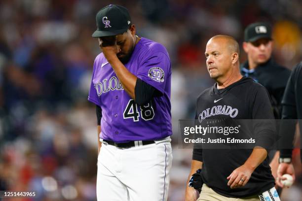 Starting pitcher German Marquez of the Colorado Rockies exits the field with a member of the training staff during the sixth inning against the St....